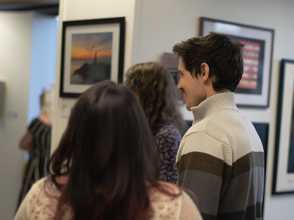 A small group of people seen talking and looking at art in a gallery